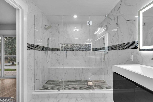 bathroom with a marble finish shower, a wealth of natural light, and a sink