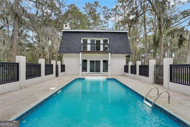 back of property featuring mansard roof, roof with shingles, and fence