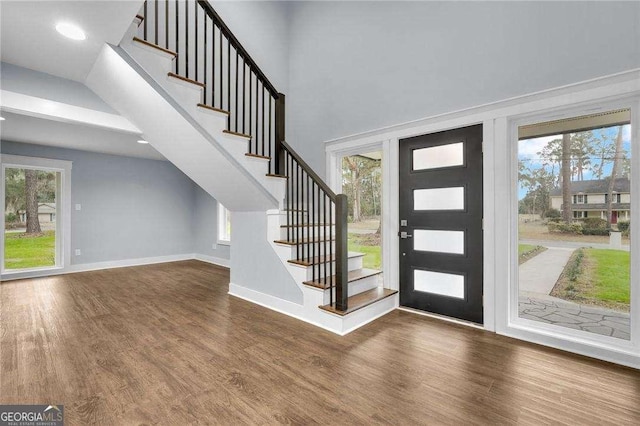 entrance foyer with a high ceiling, stairway, wood finished floors, and baseboards