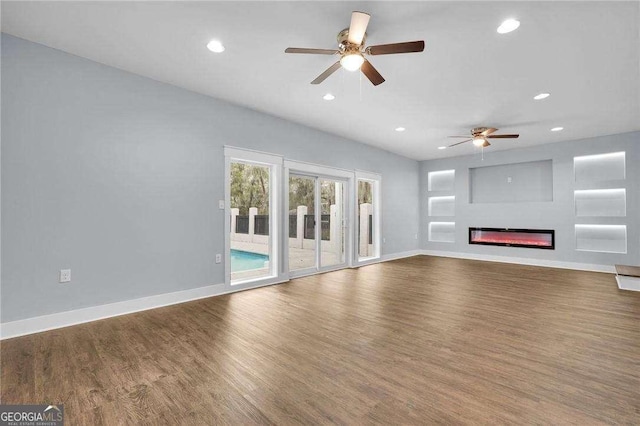 unfurnished living room featuring recessed lighting, baseboards, wood finished floors, and a glass covered fireplace