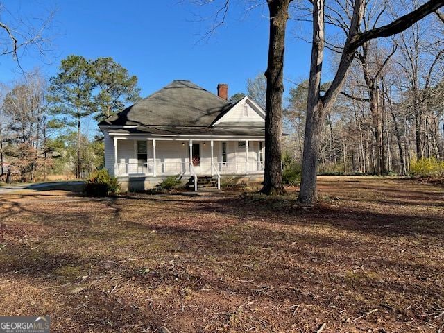 view of front facade featuring a porch and a chimney