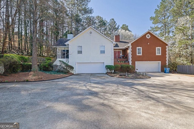 view of front of property with stairs, a garage, driveway, and a chimney