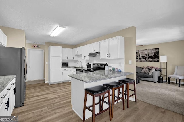 kitchen featuring under cabinet range hood, appliances with stainless steel finishes, a peninsula, and white cabinetry