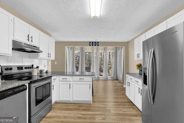 kitchen with under cabinet range hood, light wood-type flooring, a peninsula, white cabinets, and stainless steel appliances