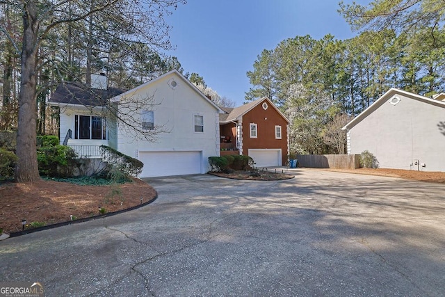 view of side of property with concrete driveway, an attached garage, and fence