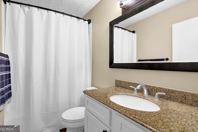 full bath featuring a textured ceiling, vanity, and toilet