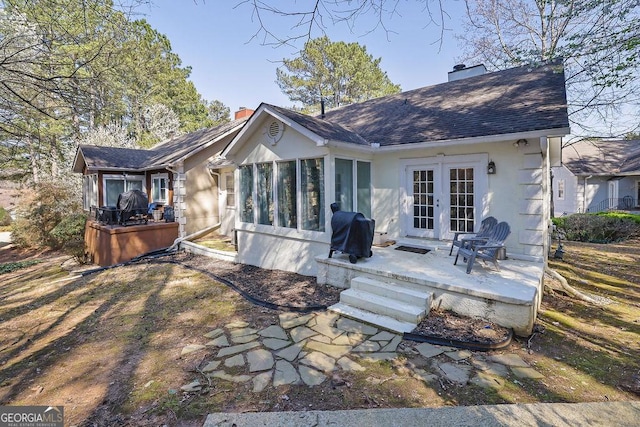 back of property featuring french doors, stucco siding, a chimney, and a patio area