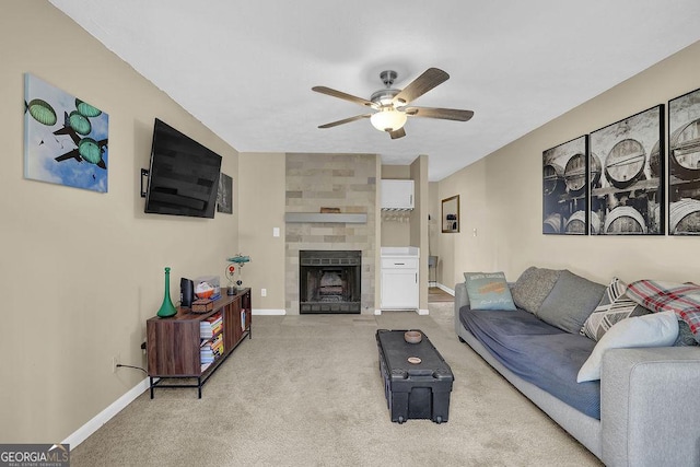 living area featuring light carpet, baseboards, a large fireplace, and ceiling fan