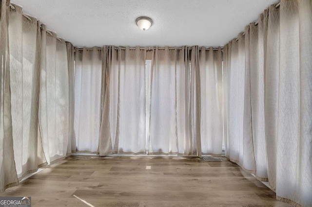 spare room featuring a textured ceiling and light wood-style floors