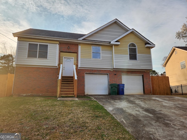 split foyer home featuring fence, entry steps, concrete driveway, a garage, and brick siding