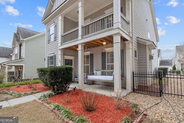 view of property exterior featuring a porch, a balcony, fence, and board and batten siding