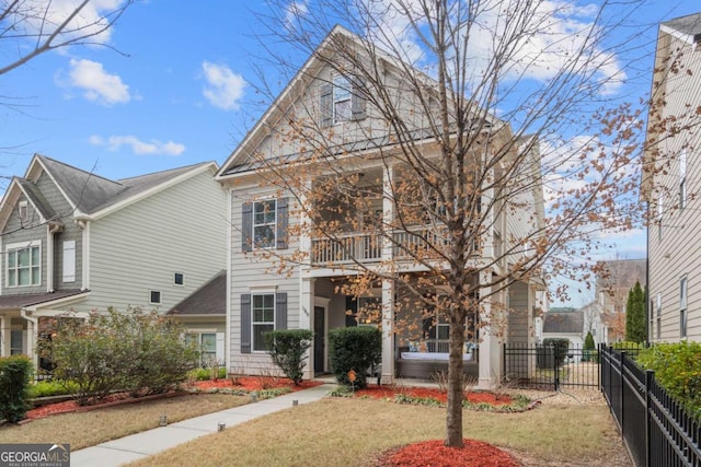 view of front of home featuring a balcony, a front yard, and fence