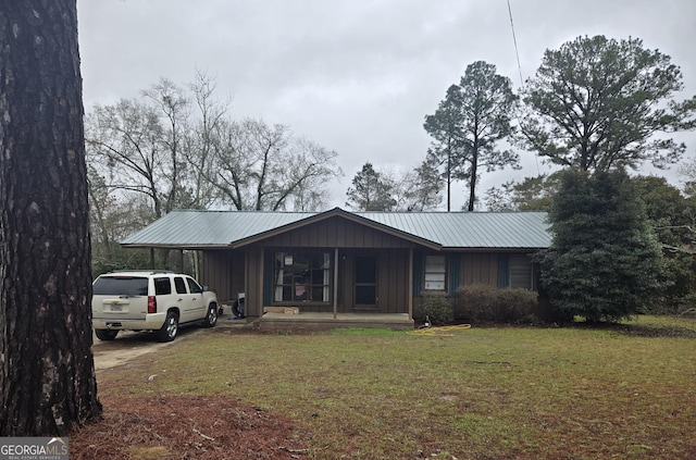 view of front facade with a front yard, covered porch, a carport, board and batten siding, and metal roof