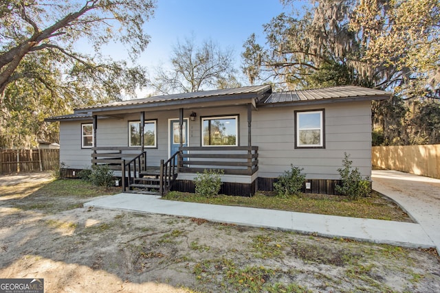 view of front of property with a porch, metal roof, and fence