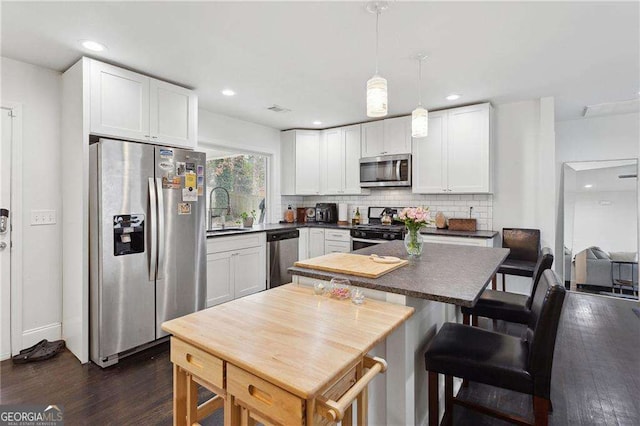 kitchen with a sink, backsplash, stainless steel appliances, white cabinets, and dark wood-style flooring