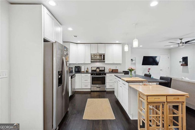 kitchen featuring tasteful backsplash, visible vents, open floor plan, stainless steel appliances, and white cabinetry