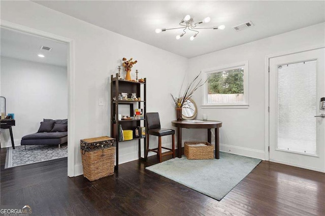interior space with visible vents, baseboards, a notable chandelier, and wood finished floors