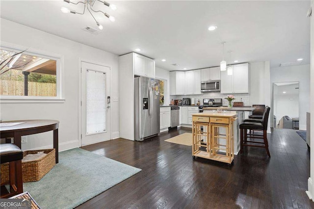 kitchen featuring stainless steel appliances, visible vents, white cabinets, and dark wood-style flooring