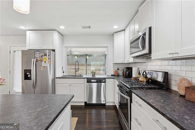 kitchen featuring tasteful backsplash, white cabinets, stainless steel appliances, and a sink
