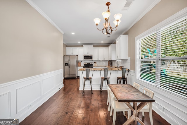 kitchen with a notable chandelier, stainless steel appliances, a peninsula, white cabinets, and dark wood-style flooring