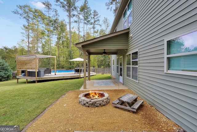 view of yard featuring fence, an outdoor pool, ceiling fan, a fire pit, and a patio area