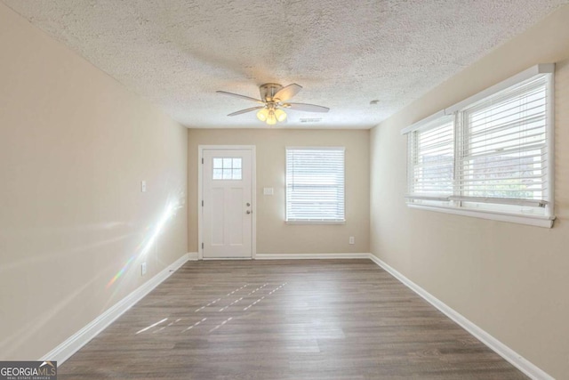 interior space with a textured ceiling, wood finished floors, baseboards, and ceiling fan