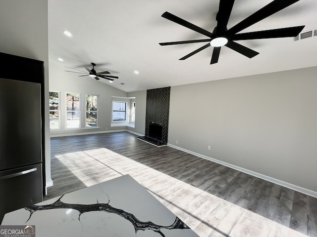 unfurnished living room featuring visible vents, a large fireplace, baseboards, dark wood finished floors, and lofted ceiling