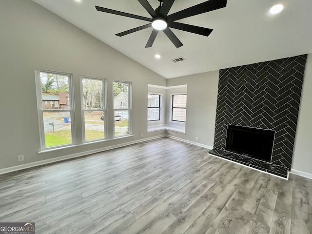 unfurnished living room featuring a ceiling fan, wood finished floors, visible vents, baseboards, and a tiled fireplace