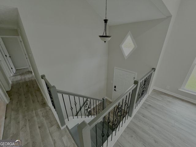 stairway featuring a wealth of natural light, high vaulted ceiling, and wood finished floors