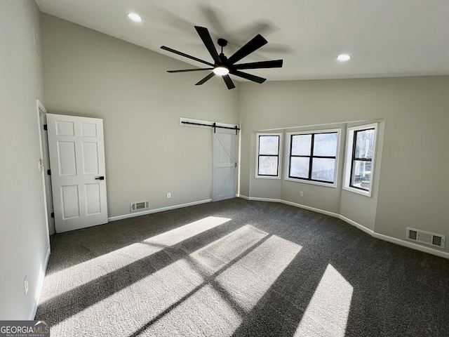 unfurnished bedroom with visible vents, baseboards, a barn door, and dark colored carpet