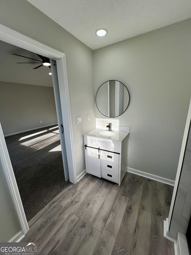 bathroom with baseboards, a ceiling fan, wood finished floors, and vanity