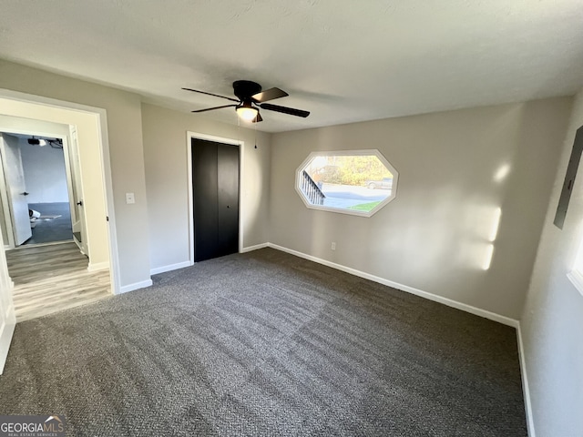 unfurnished bedroom featuring a closet, baseboards, ceiling fan, and dark carpet