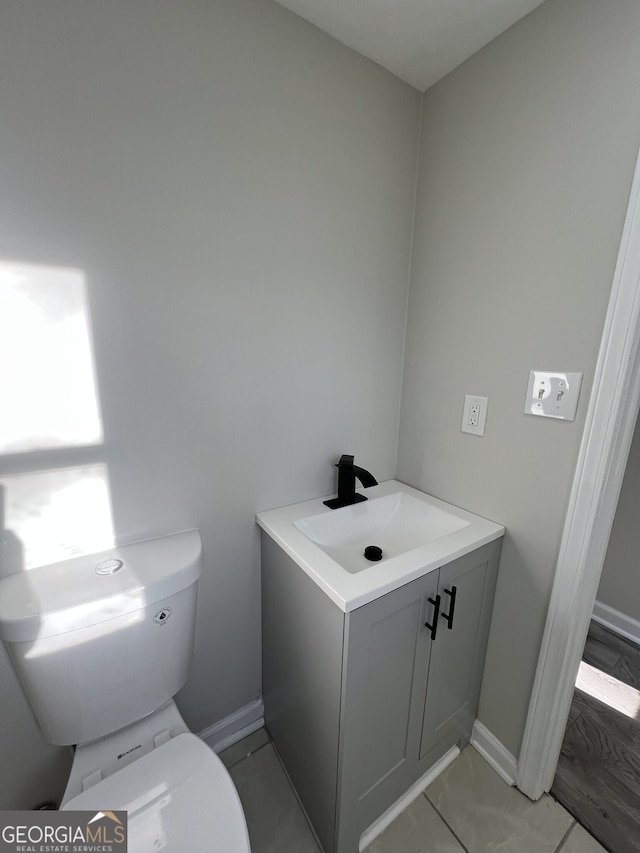 bathroom featuring toilet, vanity, and baseboards