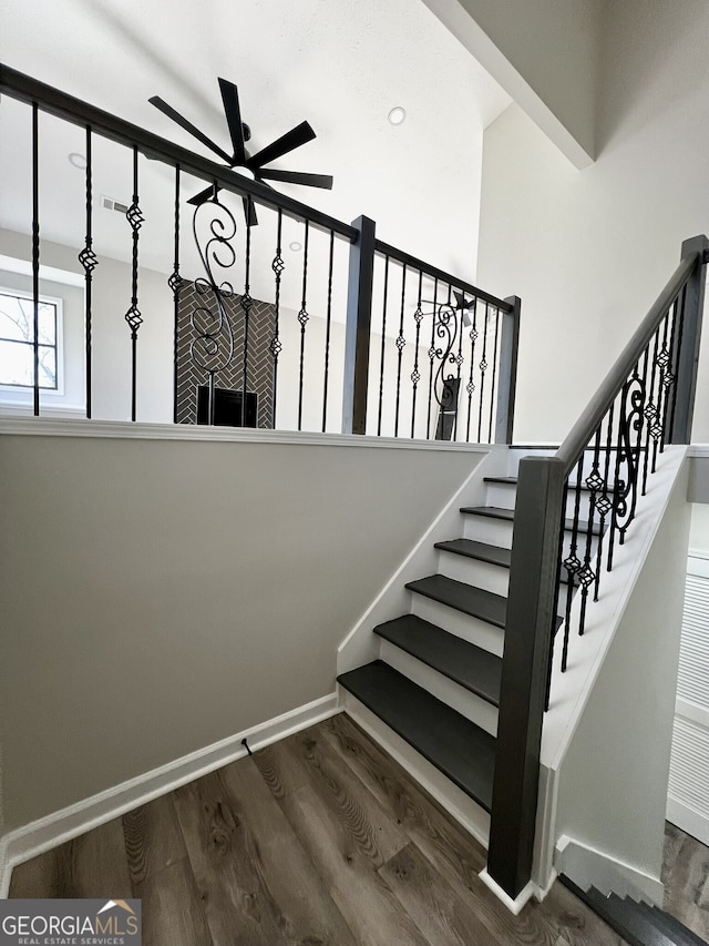 staircase featuring ceiling fan, visible vents, baseboards, and wood finished floors