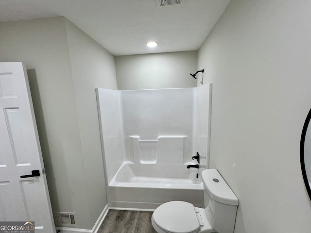 bathroom featuring toilet, wood finished floors, visible vents, and shower / bathtub combination