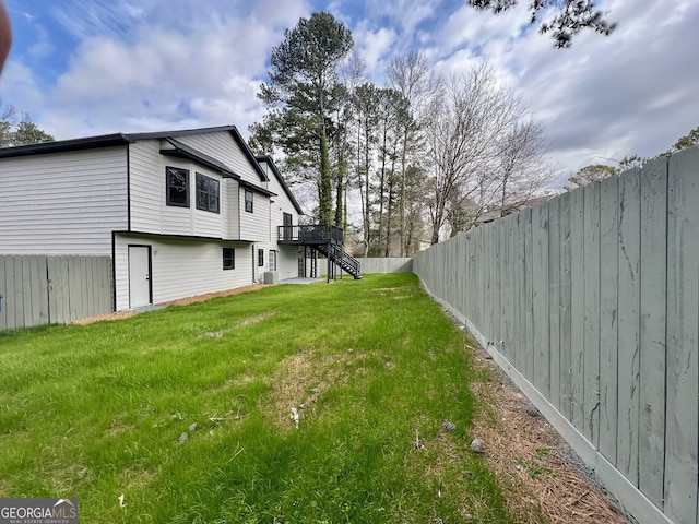 view of yard featuring a deck, a fenced backyard, and stairs