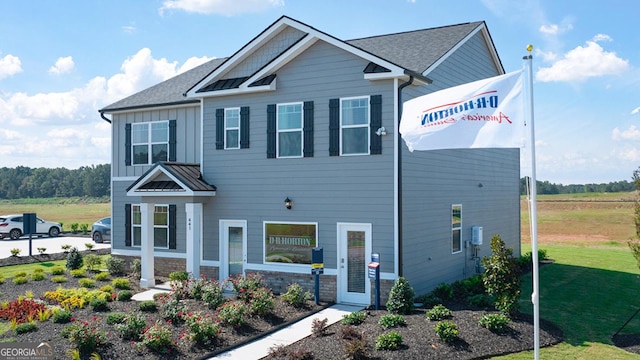 view of front of home featuring a standing seam roof, a front yard, board and batten siding, and stone siding