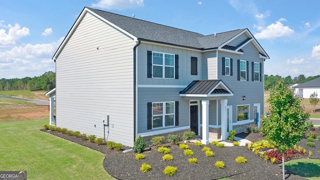 view of front of home featuring a standing seam roof, a front lawn, board and batten siding, and a shingled roof