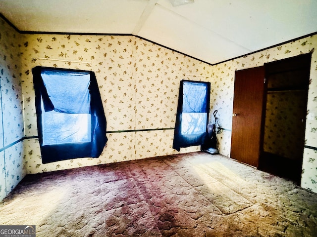 unfurnished room featuring vaulted ceiling, carpet, and ornamental molding