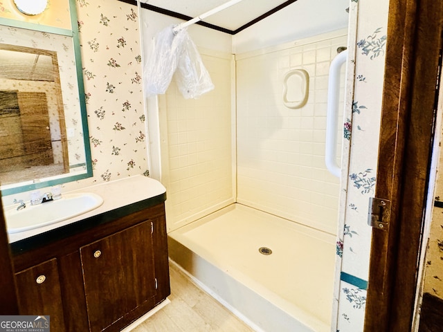 bathroom with a shower stall, wallpapered walls, and vanity