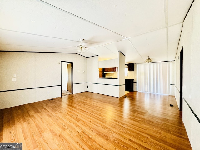 unfurnished living room featuring lofted ceiling, a ceiling fan, and wood finished floors