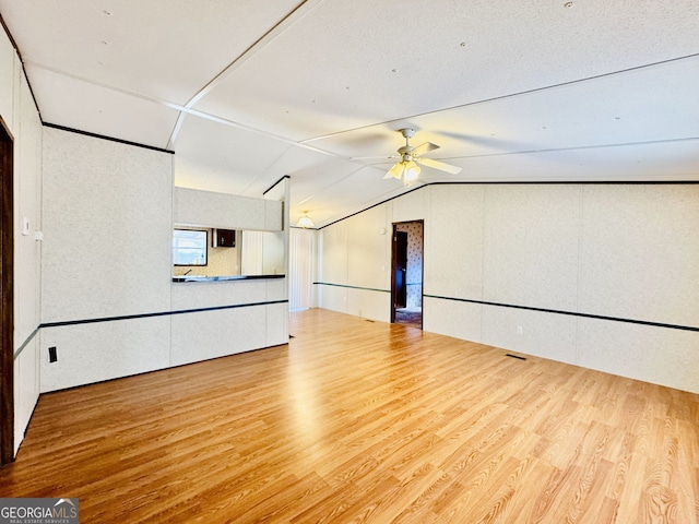 unfurnished living room with a ceiling fan, lofted ceiling, and wood finished floors