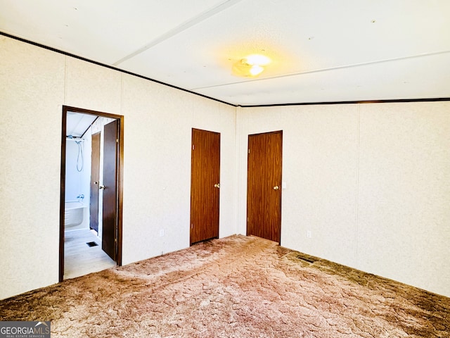 unfurnished bedroom featuring carpet floors and ensuite bathroom