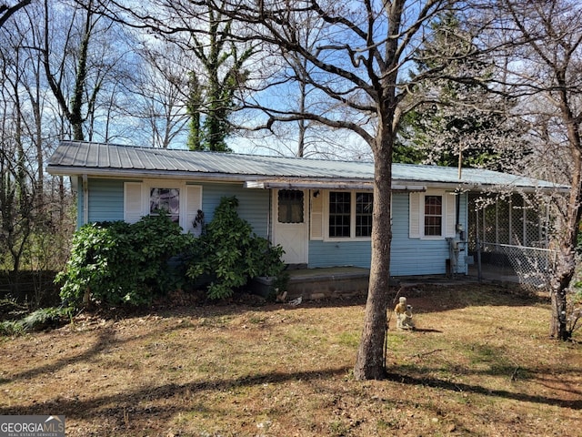 view of front of home featuring a front yard, a porch, and metal roof