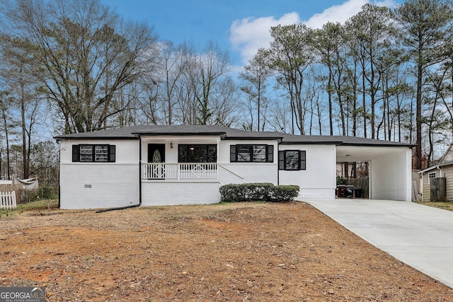 view of front of property with brick siding, fence, concrete driveway, covered porch, and a carport