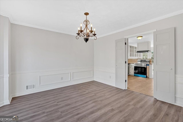 empty room featuring visible vents, ornamental molding, and wood finished floors