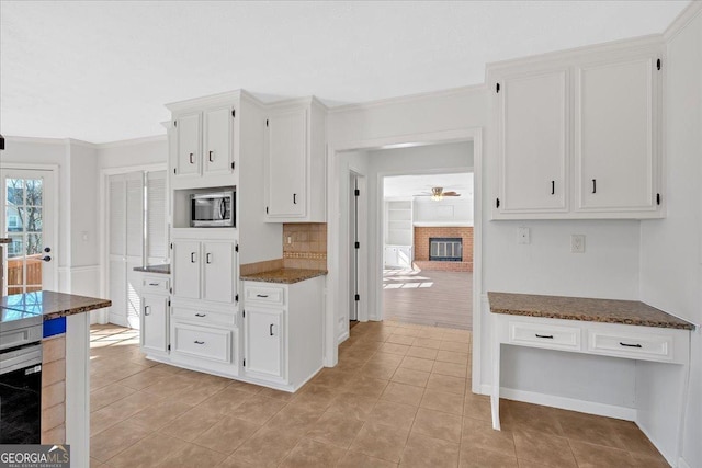 kitchen with white cabinetry, stainless steel microwave, light tile patterned floors, and a fireplace