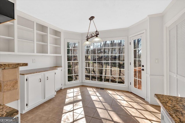 unfurnished dining area with light tile patterned floors, visible vents, and crown molding