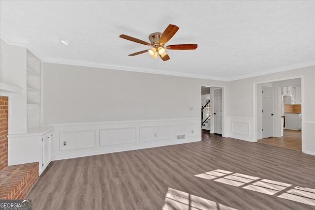 unfurnished living room with visible vents, built in shelves, light wood-style flooring, and ornamental molding