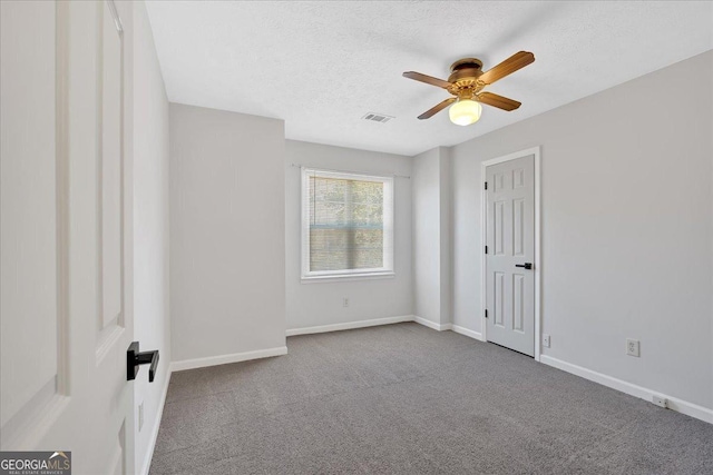 carpeted empty room with a ceiling fan, baseboards, visible vents, and a textured ceiling